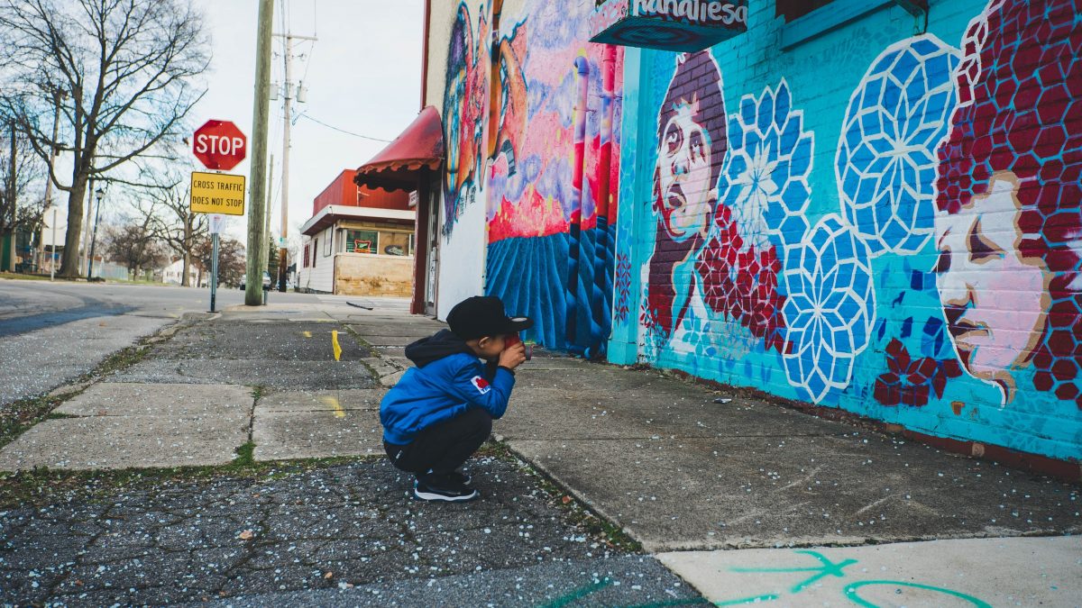 Boy taking a photo of an arts mural along a Cleveland, Ohio street