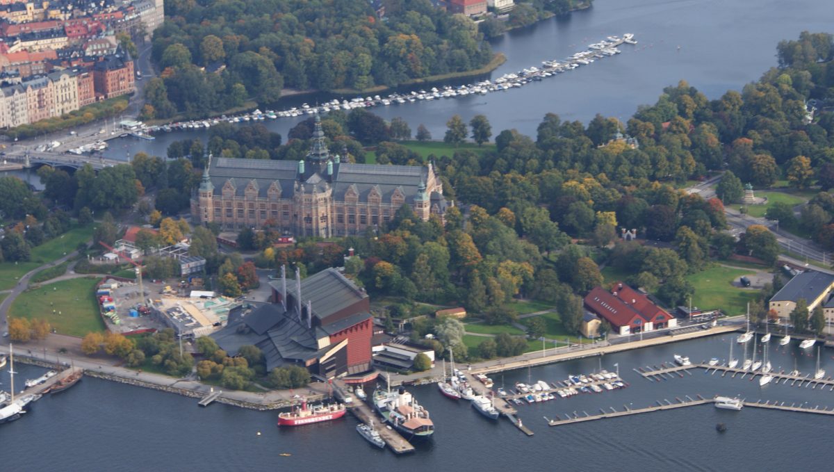 Djurgården, overhead shot with an amazing view of the the island, with forests surrounding buildings, the sea and boats Djurgården, overhead shot with an amazing view of the the island, with forests surrounding buildings, the sea and boats