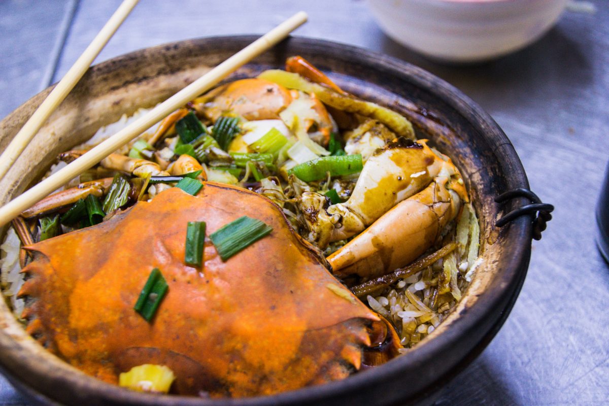 Different food ingredients in a Chinese hot pot with chopsticks.