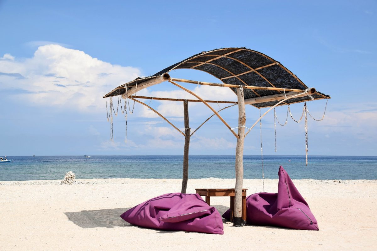 Two bean bags sit below a makeshift beach umbrella in Gili Islands, Indonesia