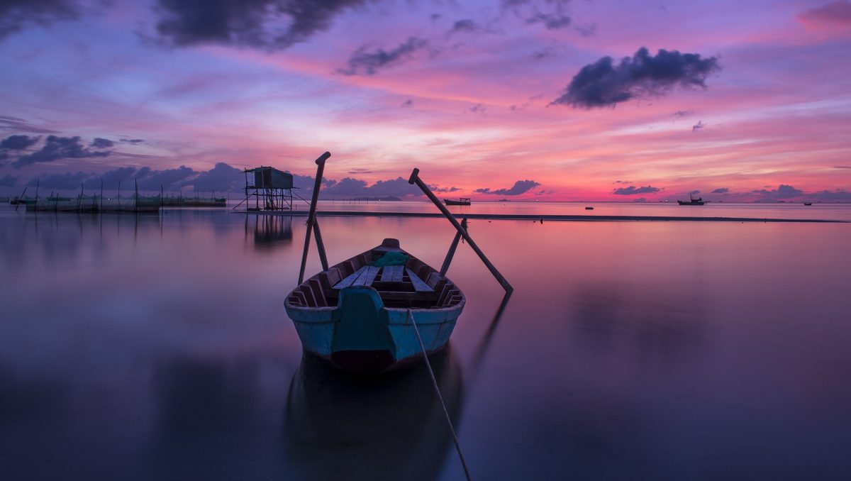 A boat sits on the calm waters as the sun rises in Phu Quoc, Vietnam