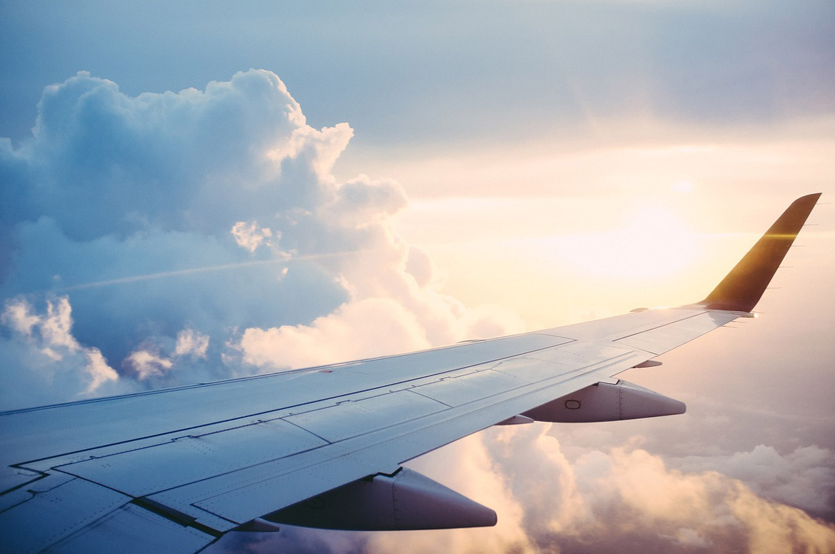 photo of the right wing of an airplane with clouds at the background