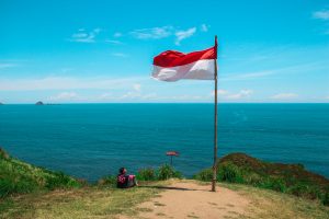an indonesian flag on a cliff overlooking the beach
