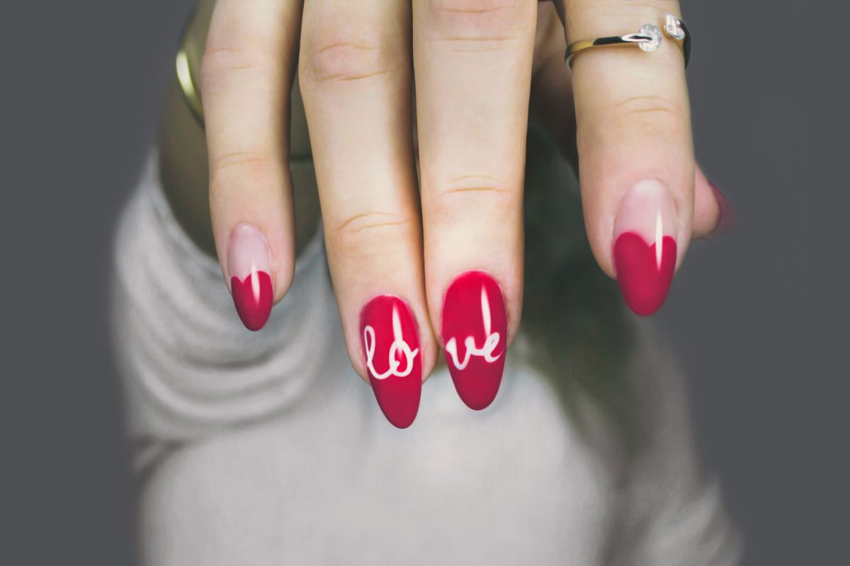 Photo of a woman’s fingers from the top with a ring on the index finger and the nails painted magenta, fully magenta with the word ‘love’ across the ring and middle finger, and heart-shaped magenta colors that fill half of the fingernail on the pinky and index fingers Photo of a woman’s fingers from the top with a ring on the index finger and the nails painted magenta, fully magenta with the word ‘love’ across the ring and middle finger, and heart-shaped magenta colors that fill half of the fingernail on the pinky and index fingers