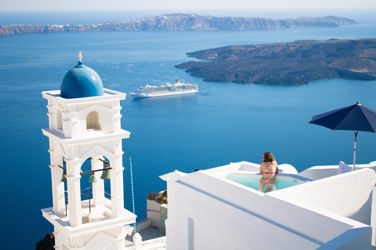 A woman swims in a pool overlooking the sea in Santorini, Greece