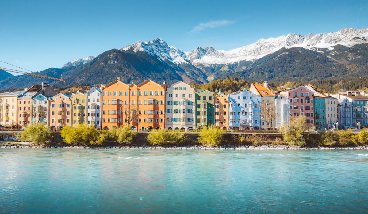 Panoramic view of the historic city center of Innsbruck with colorful houses along Inn river and famous Austrian mountain summits in the background in beautiful evening light at sunset, Tyrol, Austria