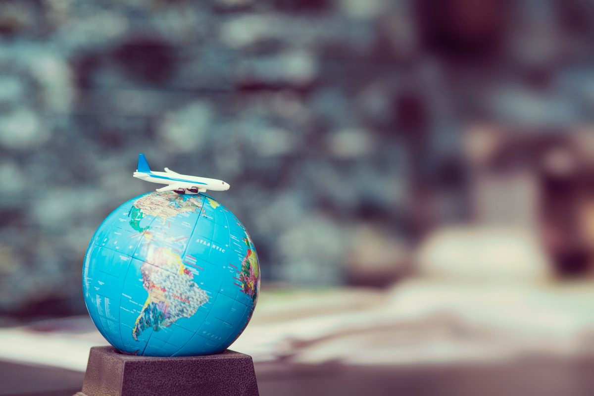 a globe with a toy airplane on top of it Miniature airplane figure on top of small world globe