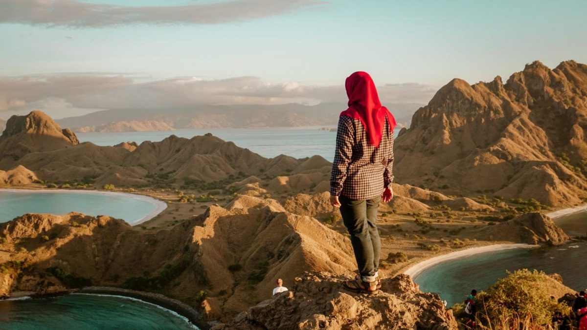 woman standing on a cliff woman standing on cliff surrounded by brown rocky mountains