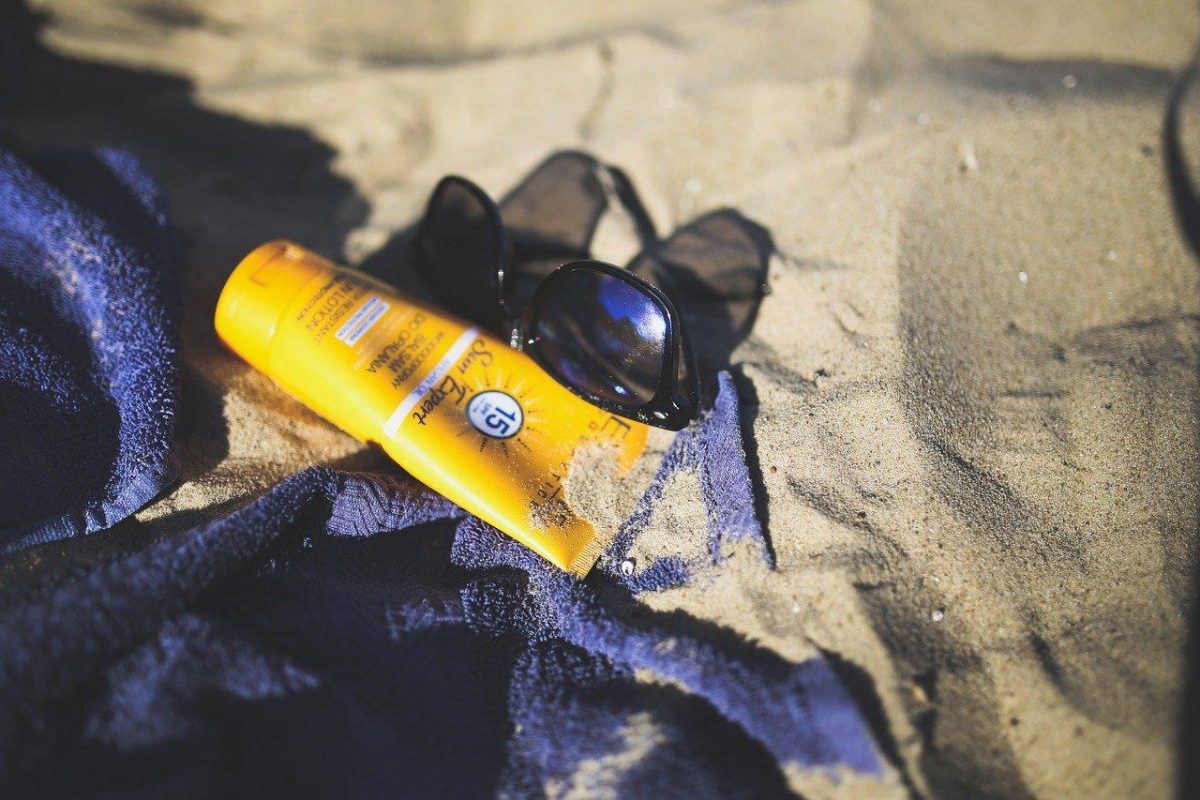 photo of sunblock and sunglasses on sand photo of sunblock and sunglasses on sand