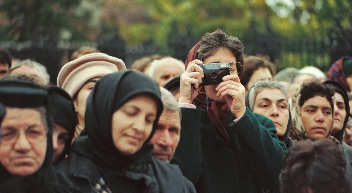 Man capturing picture surrounded by Romanian people