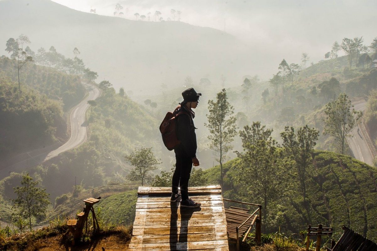 A man stands at the end of a trail overlooking the mountainous region below in Bandung, Indonesia