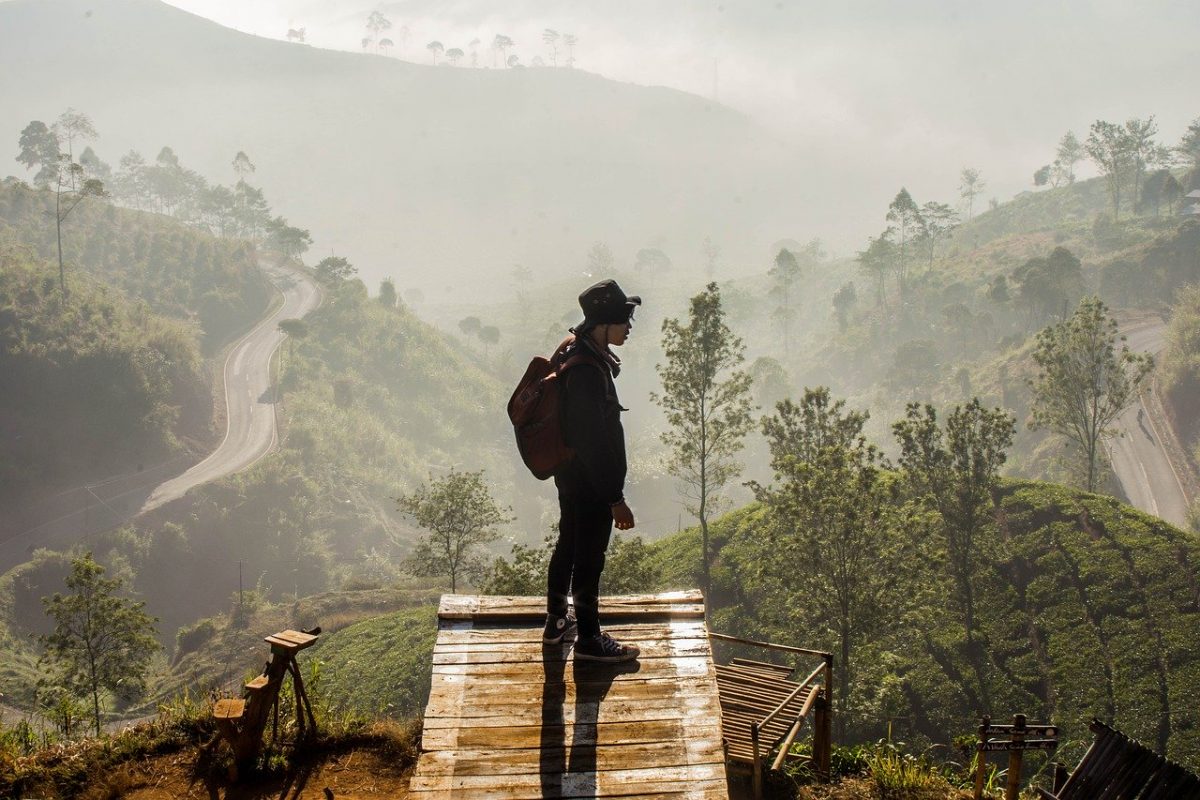 Bandung, Indonesia A man stands at the end of a trail overlooking the mountainous region below in Bandung, Indonesia