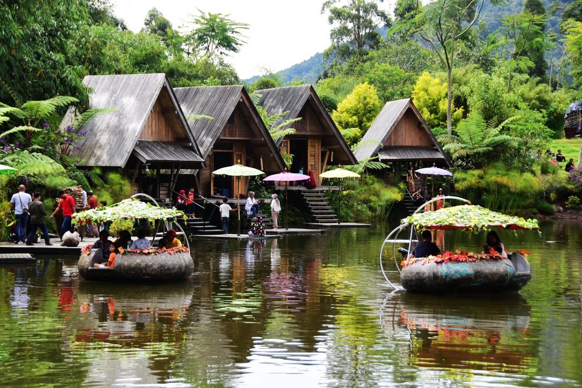 Floral boats float on a lake lined with huts on the edges in Dusun Bambu, Bandung, Indonesia Floral boats float on a lake lined with huts on the edges in Dusun Bambu, Bandung, Indonesia