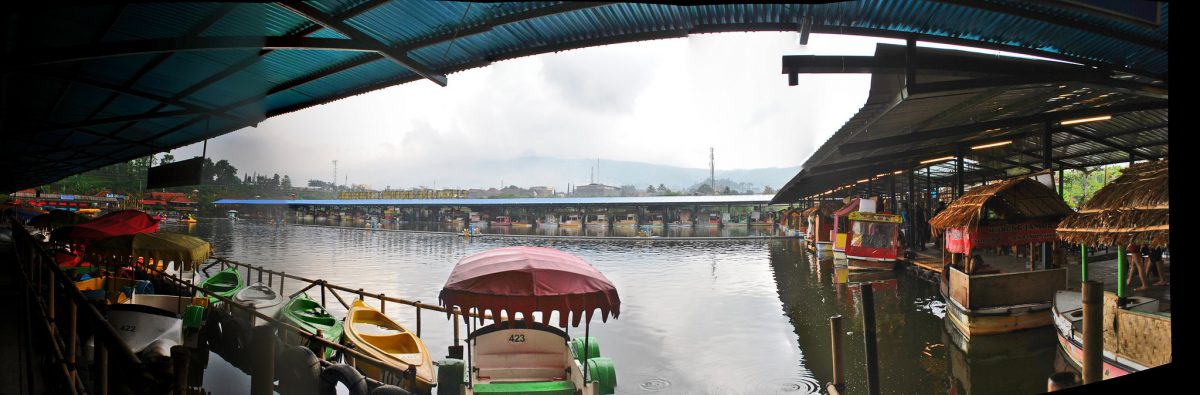 Floating food stalls and boats line the edges of a lake in Lembang Floating Market, Bandung, Indonesia