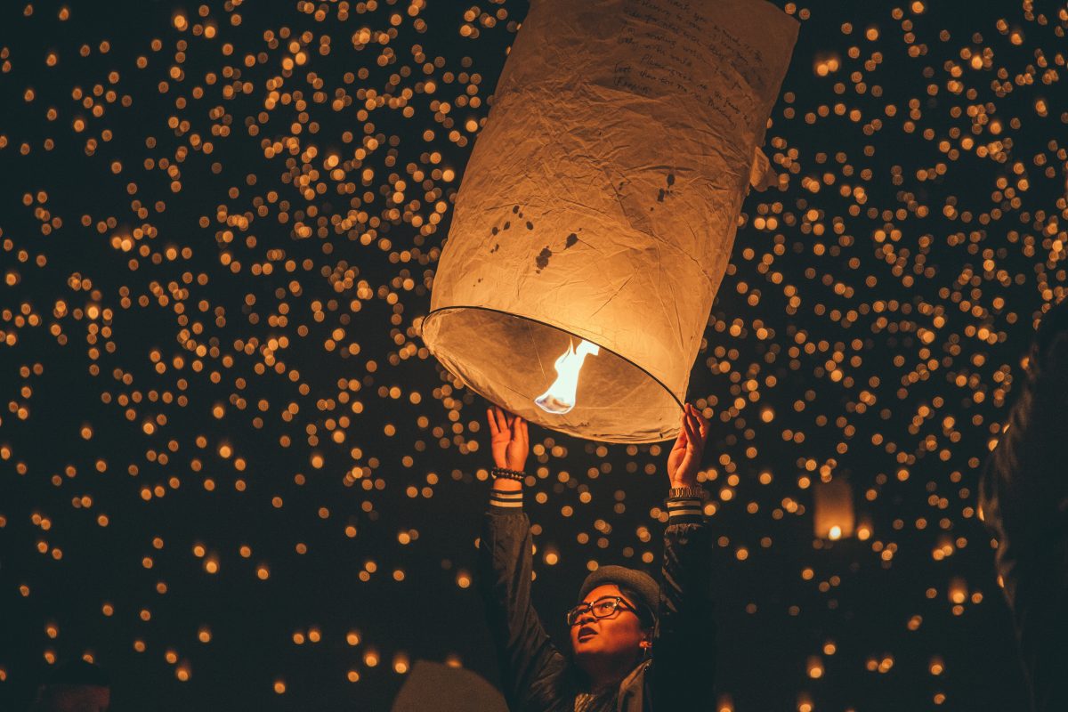 Tourist holding on to lit lantern during Thailand festival
