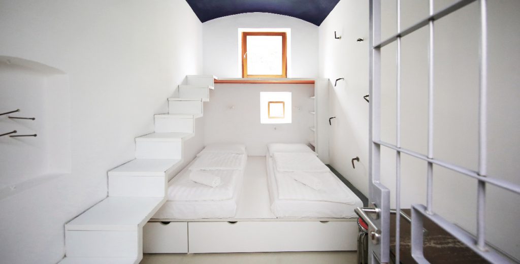 Double bed inside of prison cell, with prison bars flung open