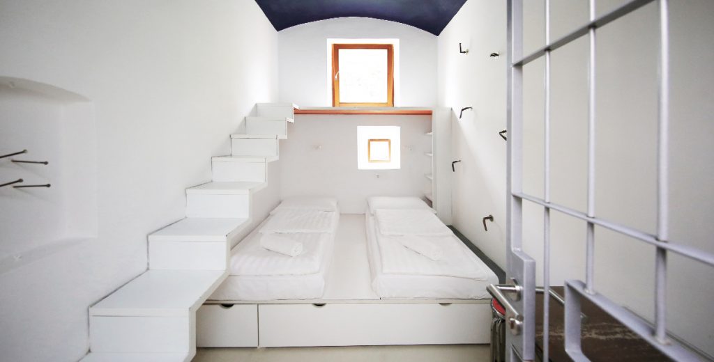 Double bed inside of prison cell, with prison bars flung open Double bed inside of prison cell, with prison bars flung open