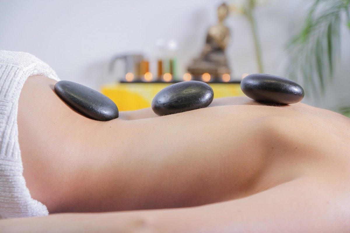 a woman lying down with heated stones on her back