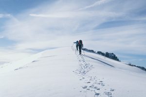 two people trekking in an steep snow mountain