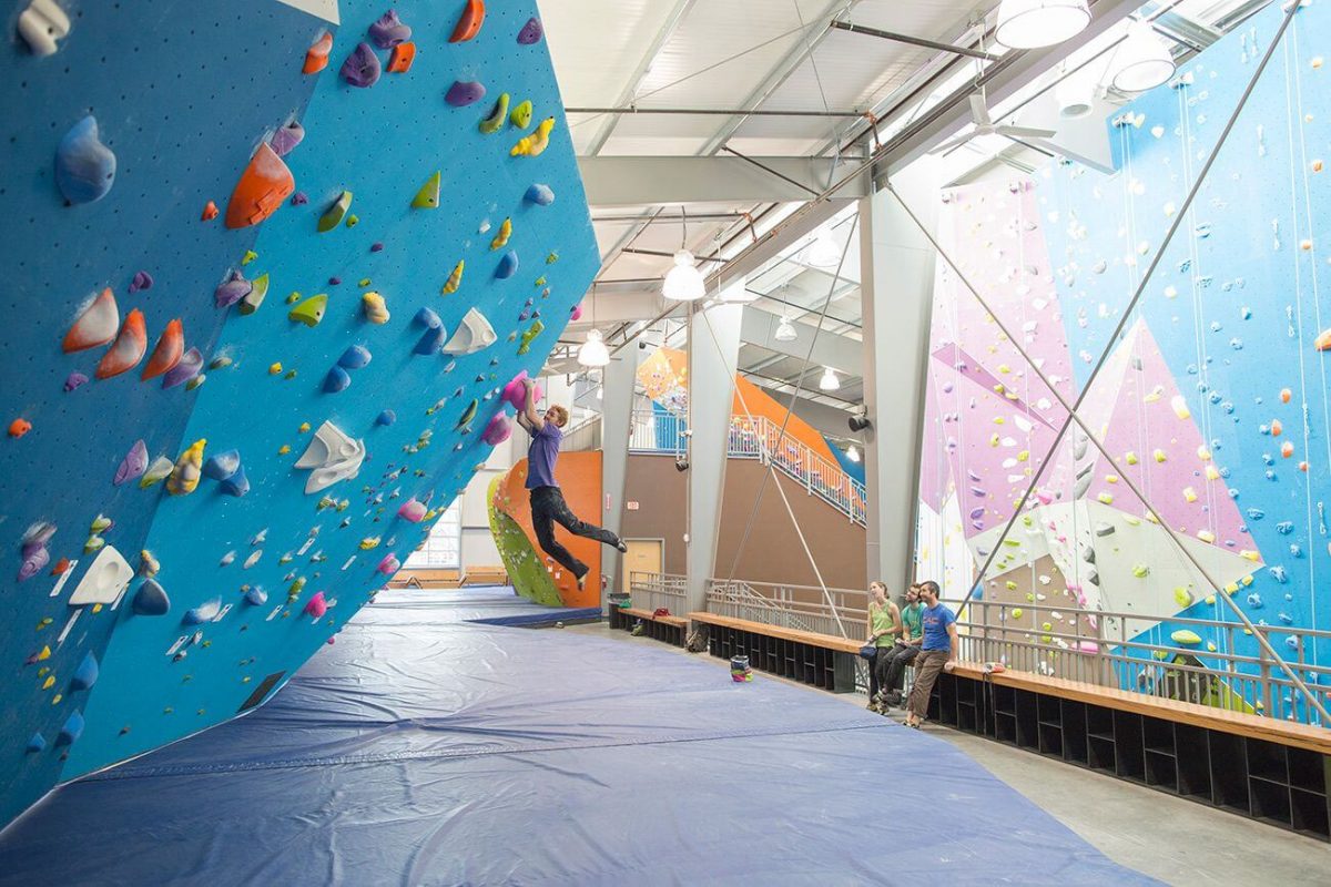 three people watching a man boulder three people watching a man boulder