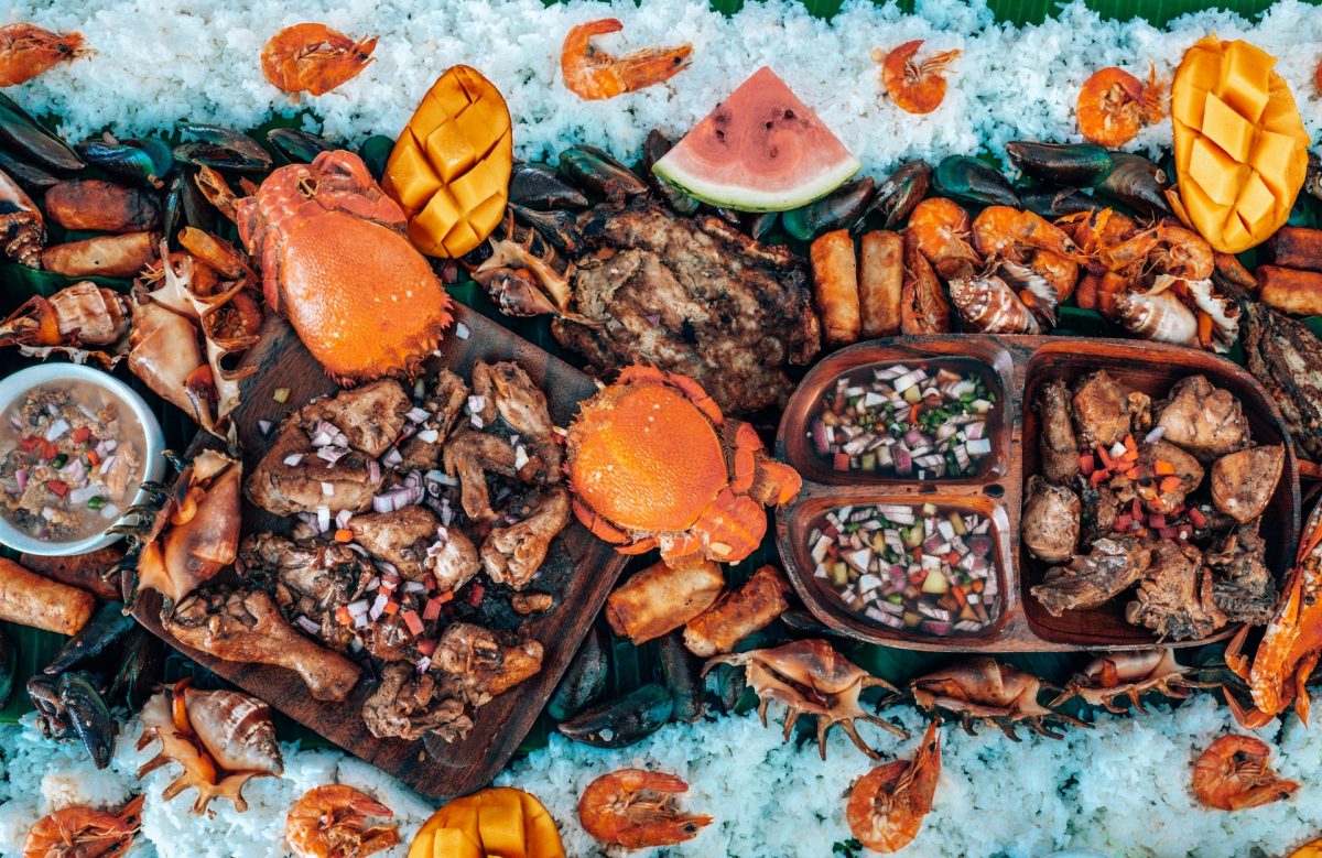 a table filled with seafood, meat, fruits, and rice