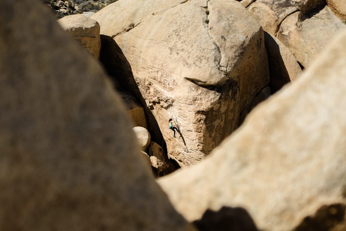 a woman climbing a bouldering area in Joshua Tree National Park a woman climbing a bouldering area in Joshua Tree National Park