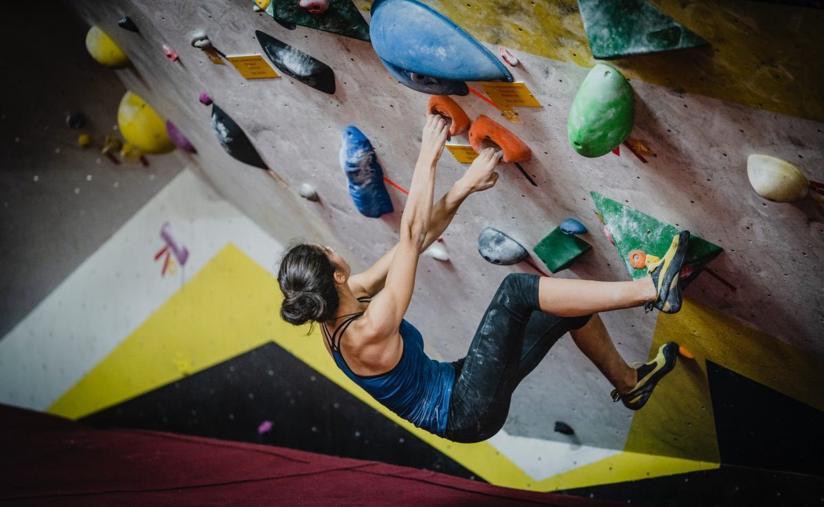 a woman bouldering in an indoor gym a woman bouldering in an indoor gym