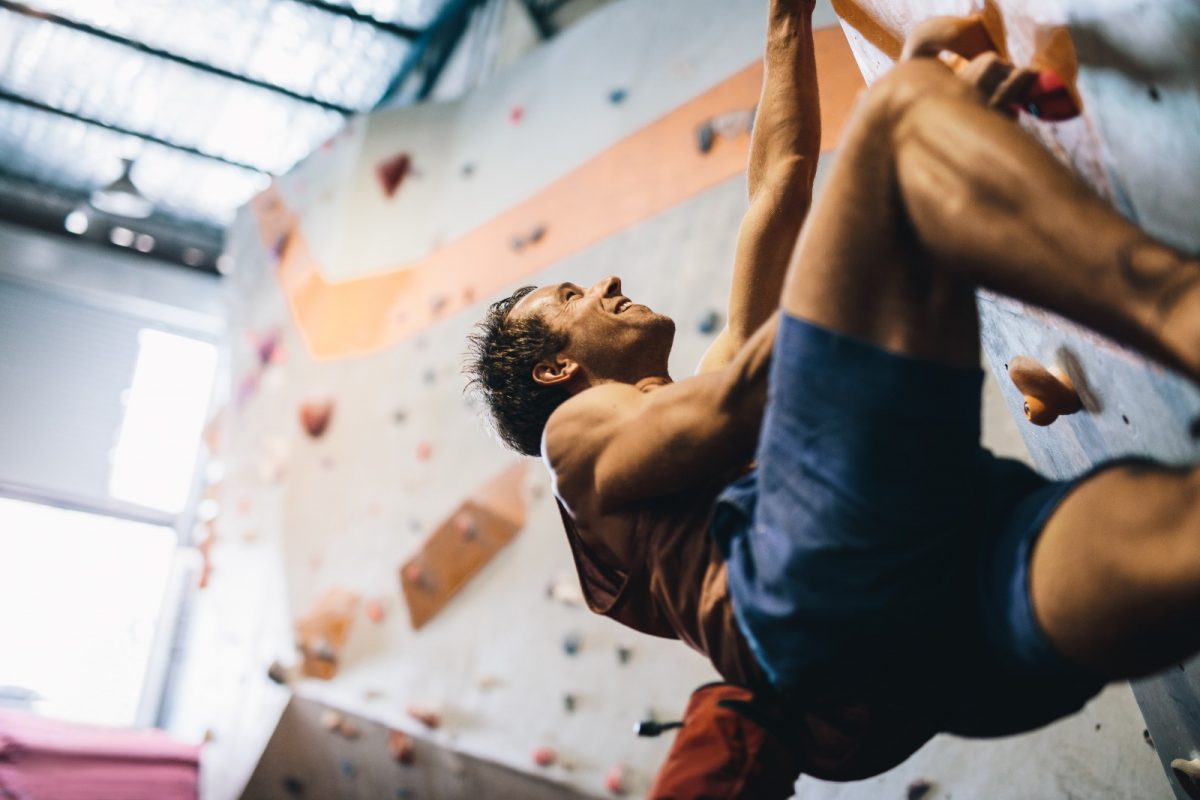 a man happily bouldering a tall wall a man happily bouldering a tall wall
