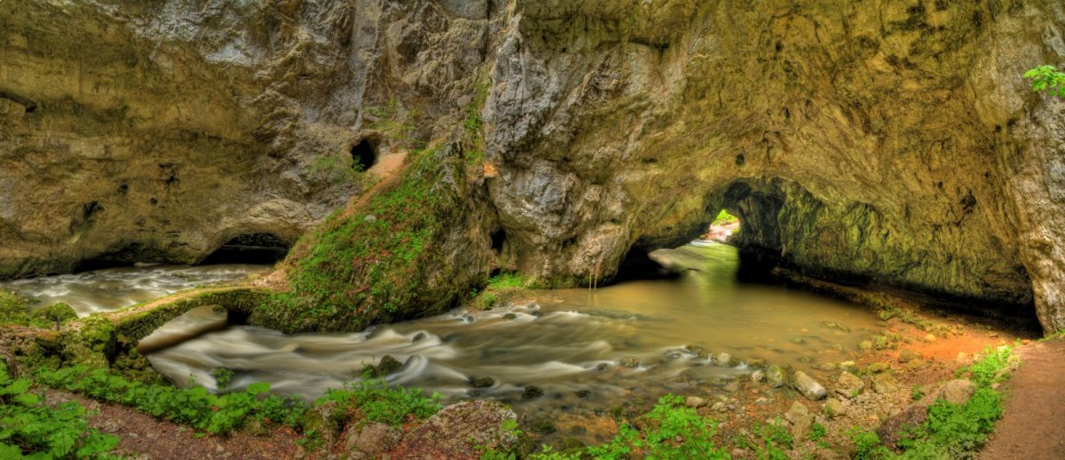 A massive cave with rapids beneath it