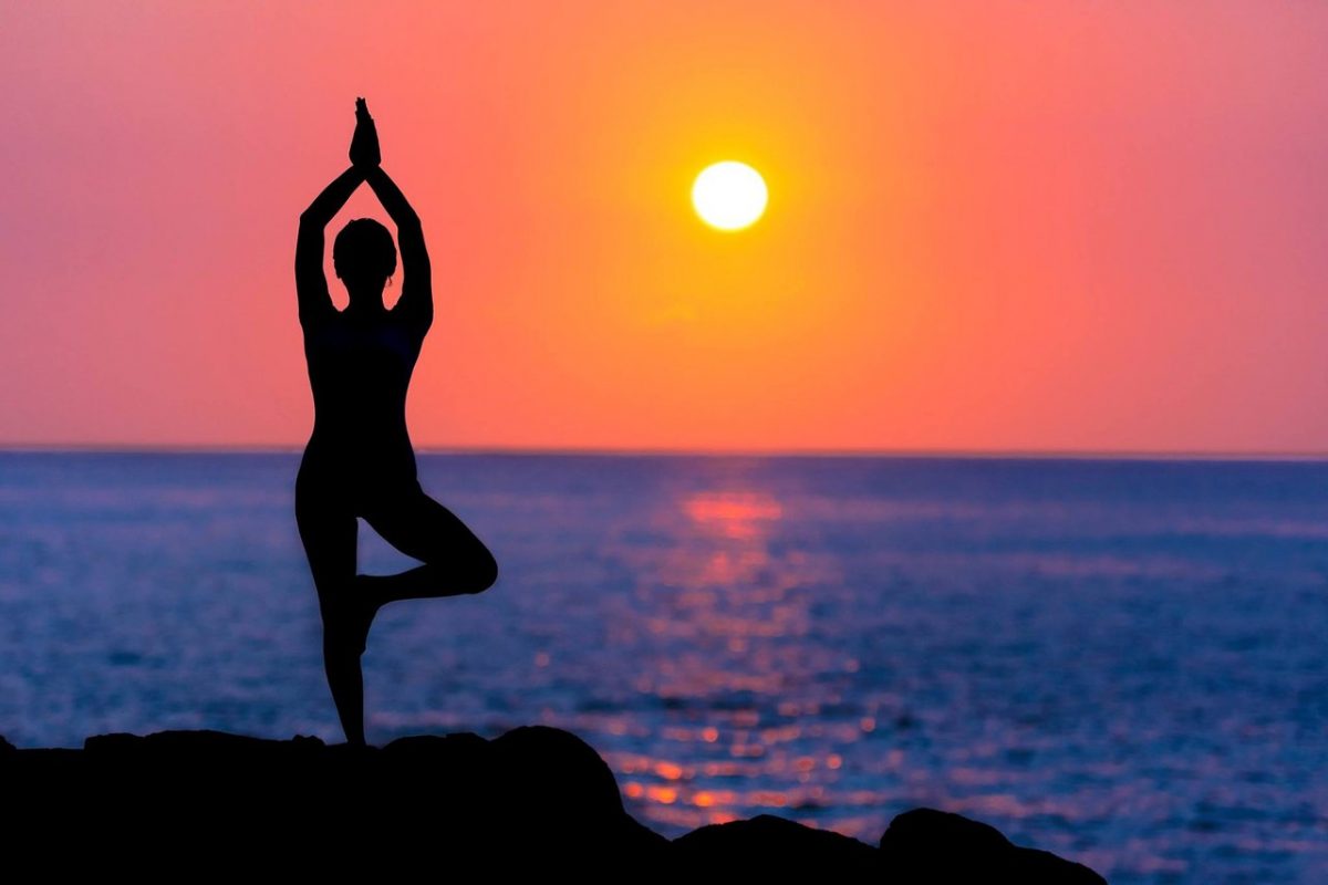 A woman doing yoga in front of the yellow and purple skies