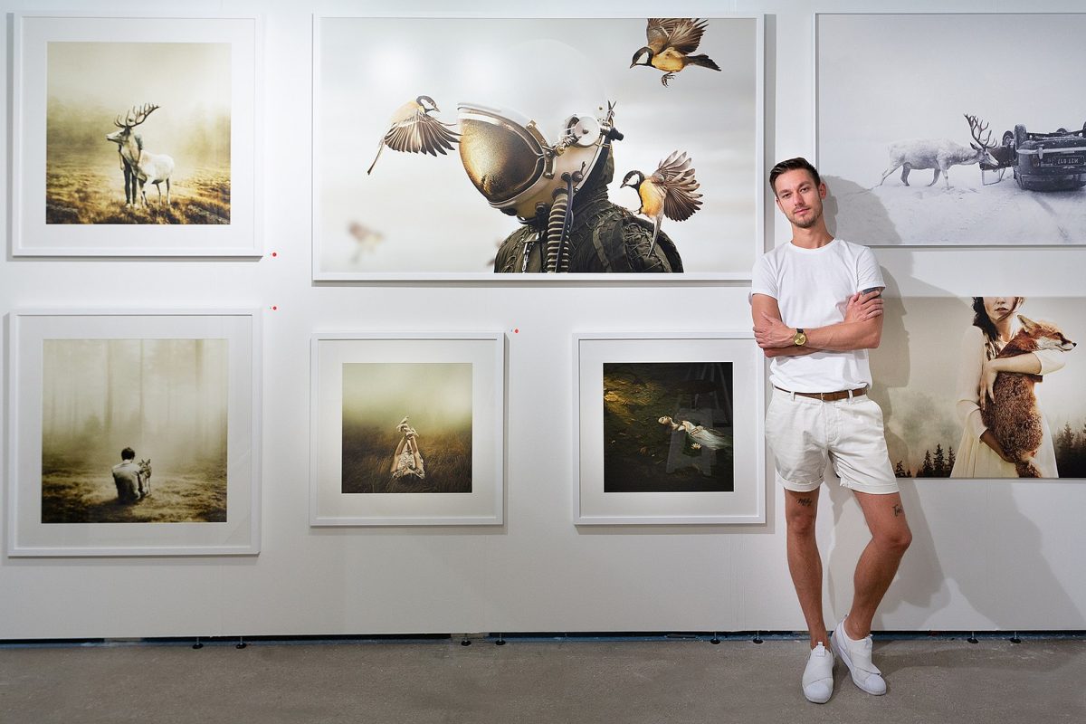 A photographer posing with his artworks in Art Basel A photographer posing with his artworks in Art Basel