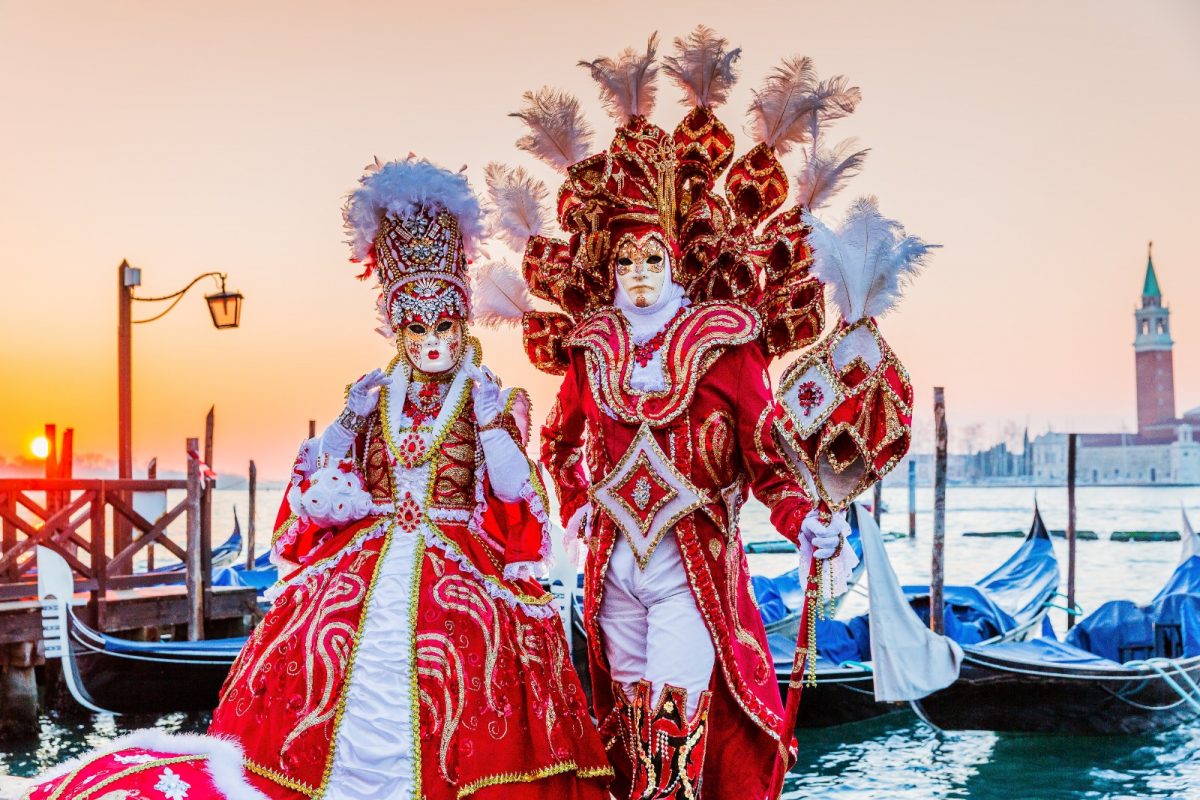 a masked couple dressed extravagantly in red