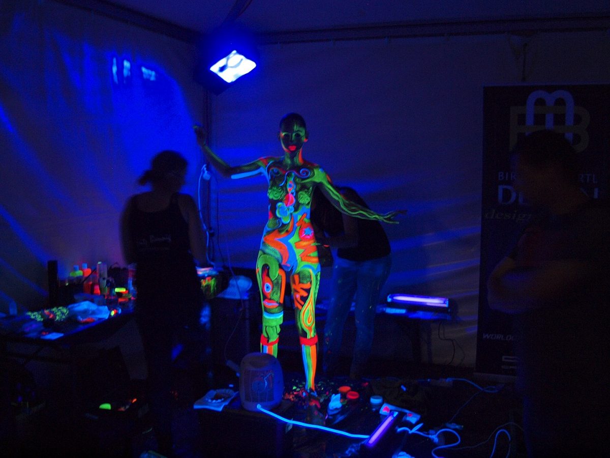 a woman being painted with neon color body paintings
