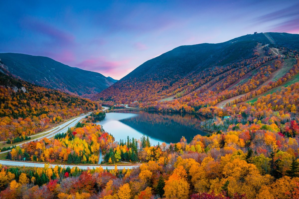 a lake surrounded by mountains dotted with orange trees, car camping