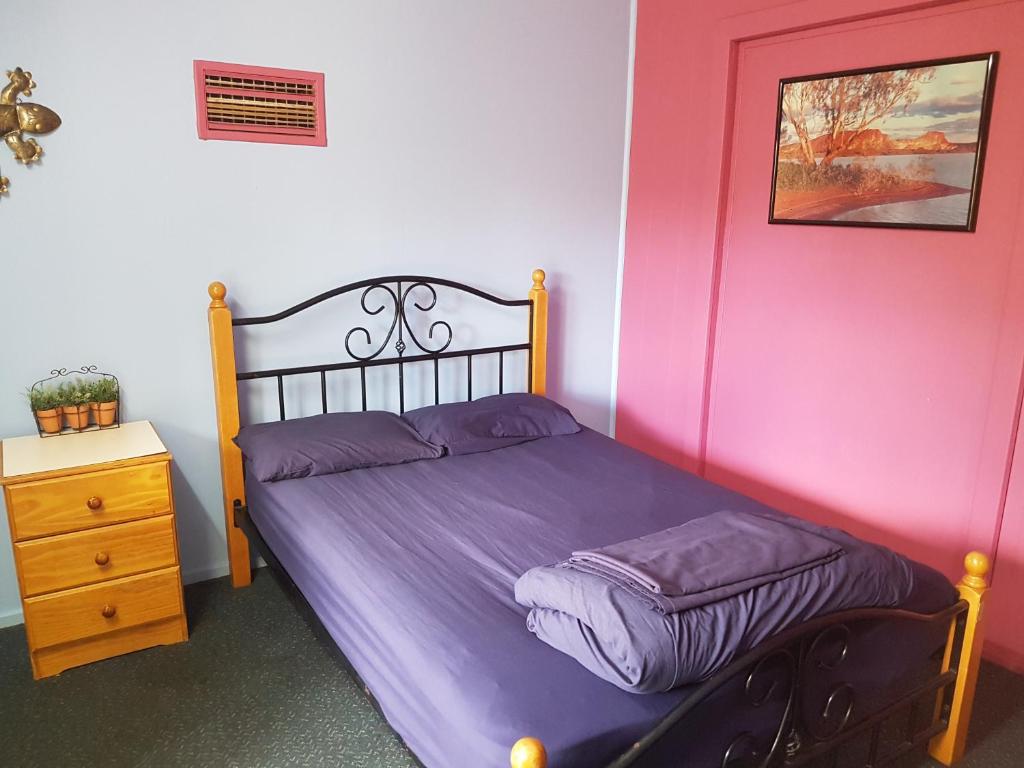 a bed with purple sheets in a room at Alice Lodge Backpackers