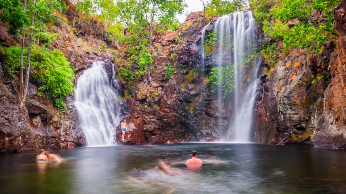 people swimming on a falls at litchfield national park