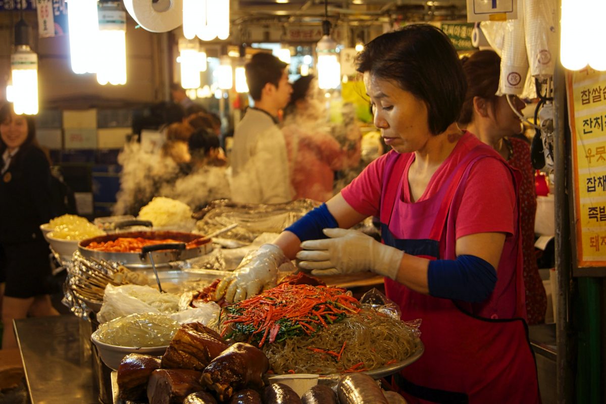 a vendor mixing Japchae at gwangjang market a vendor mixing Japchae at gwangjang market