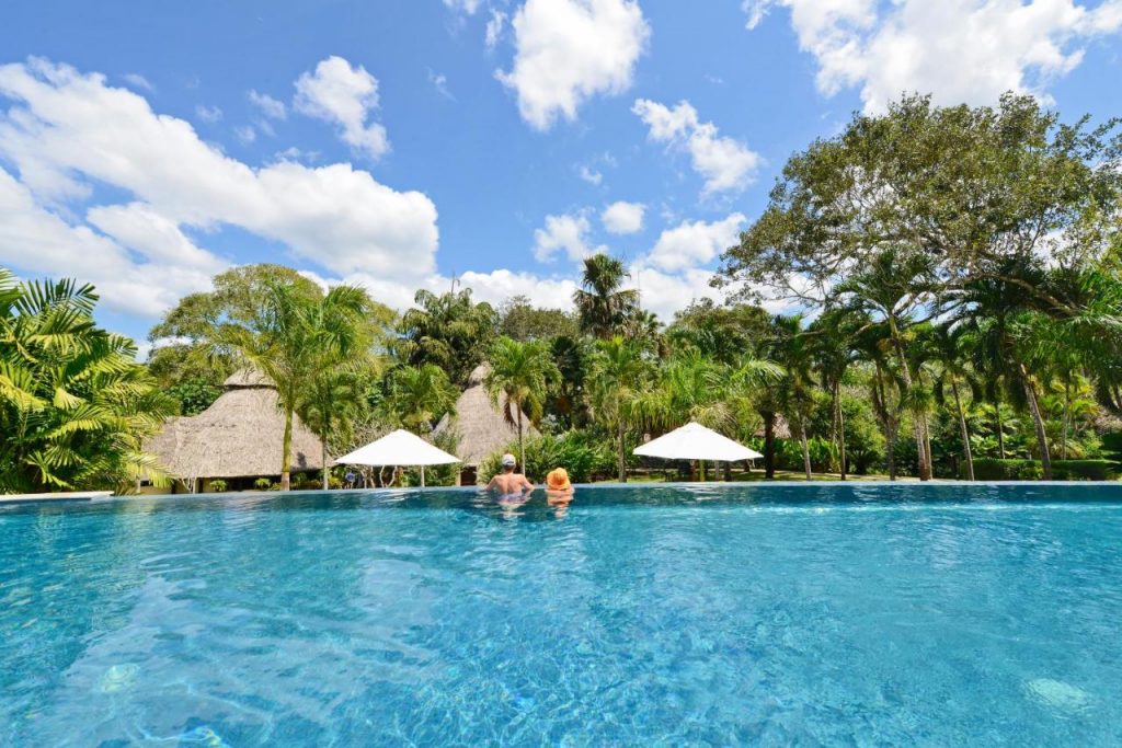 Two tourists lounging in Chaa Creek's pool facing the jungle