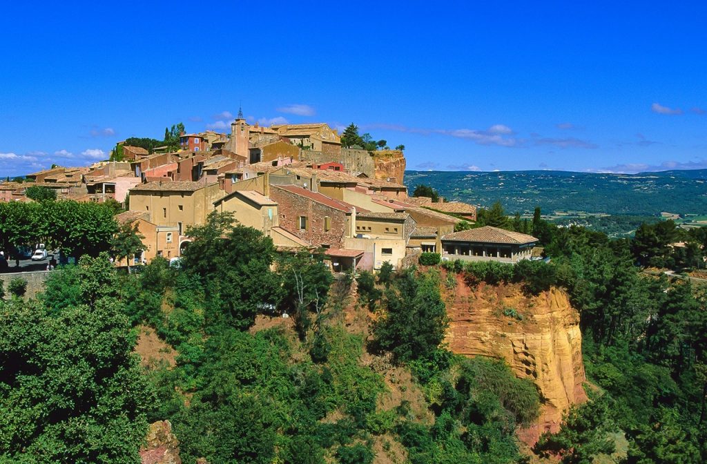 Ochre cliffs and orange-hued houses in Roussillon at the French countryside