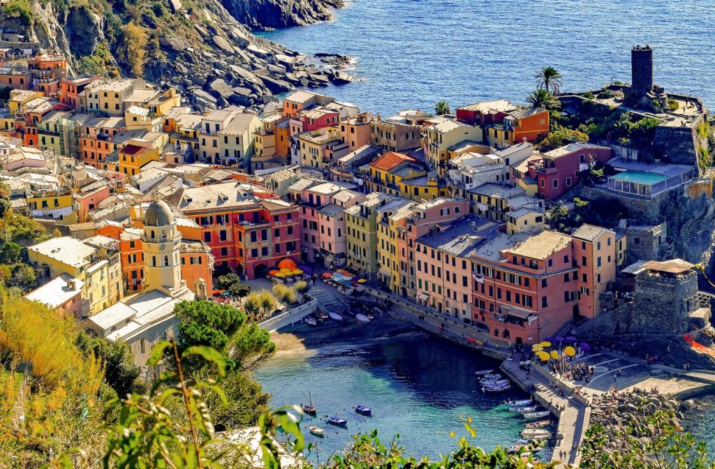 Vernazza's pastel houses and harbor as seen from the top of a cliff during the day