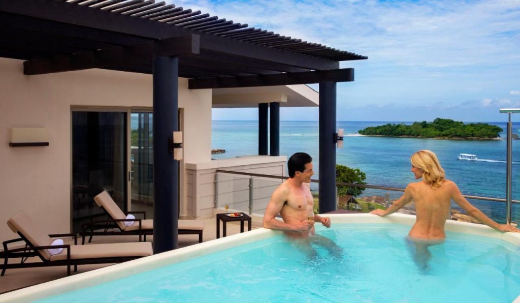 Topless couple enjoying the private pool and beach views.