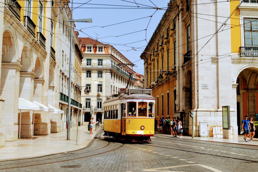 Passengers aboard a yellow tram along the streets of Lisbon.