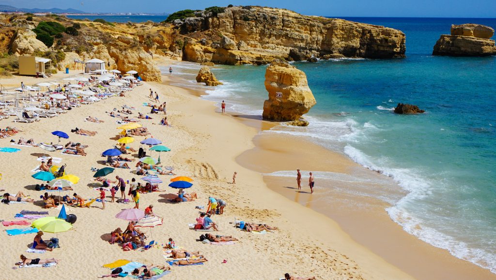 Vacationers on the beach shore during summer, the best time to visit Portugal for sunseekers.