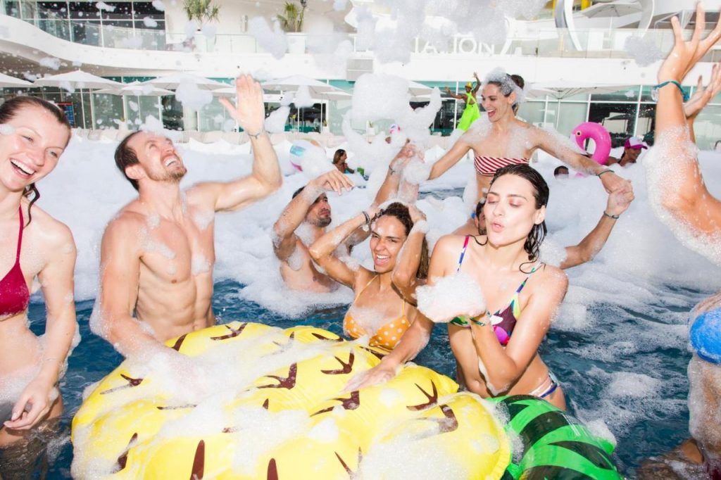 People having a foam party in a swimming pool.