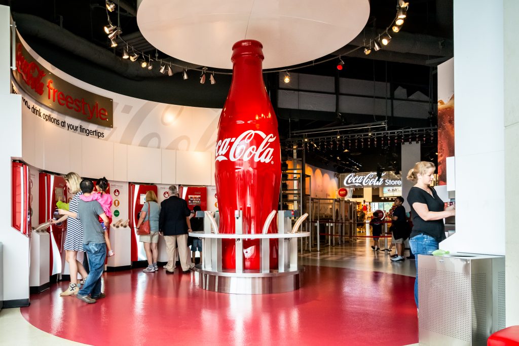 People tasting samples at the World of Coca Cola factory; a giant red coca cola bottle in the center. People tasting samples at the World of Coca Cola factory; a giant red coca cola bottle in the center.