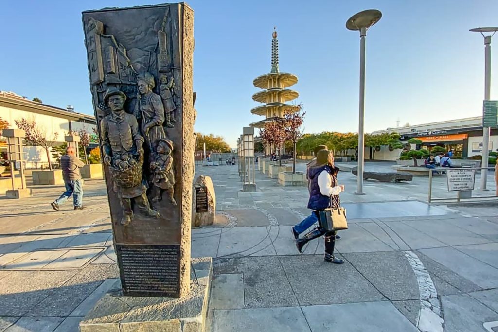 An interpretive sculpture detailing the history of the Japanese community in San Francisco, with people walking in the background.