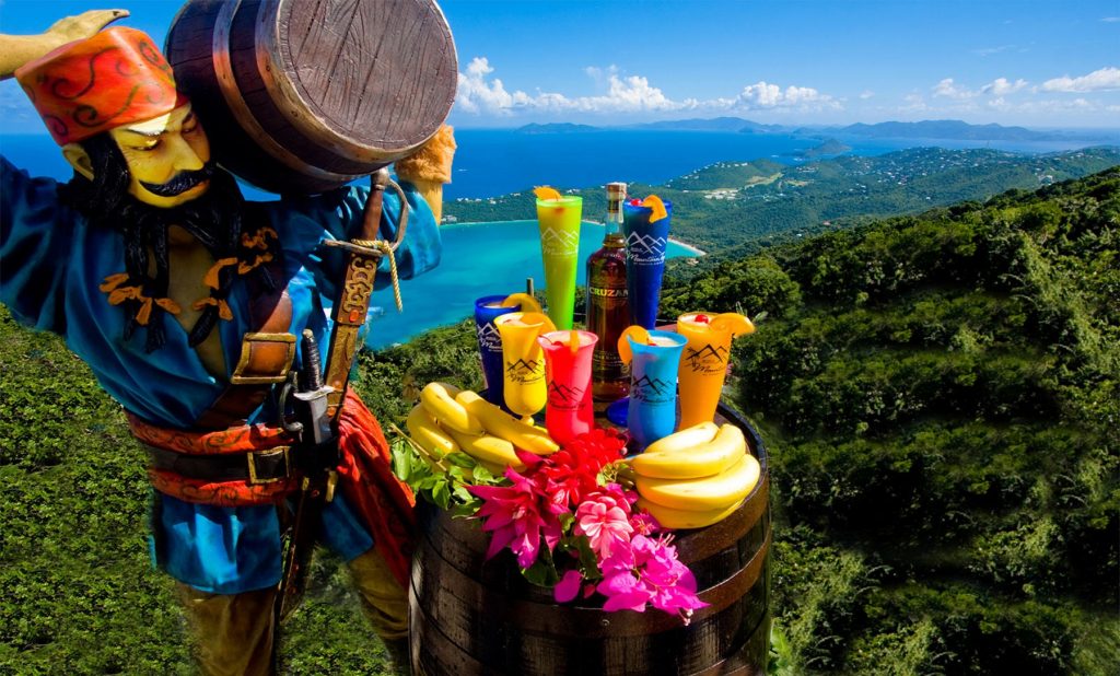 Pirate statue carrying a barrel, next to a table with bananas, rum, and banana daiquiri on top of Mountain Top in St. Thomas, overlooking Magens Bay