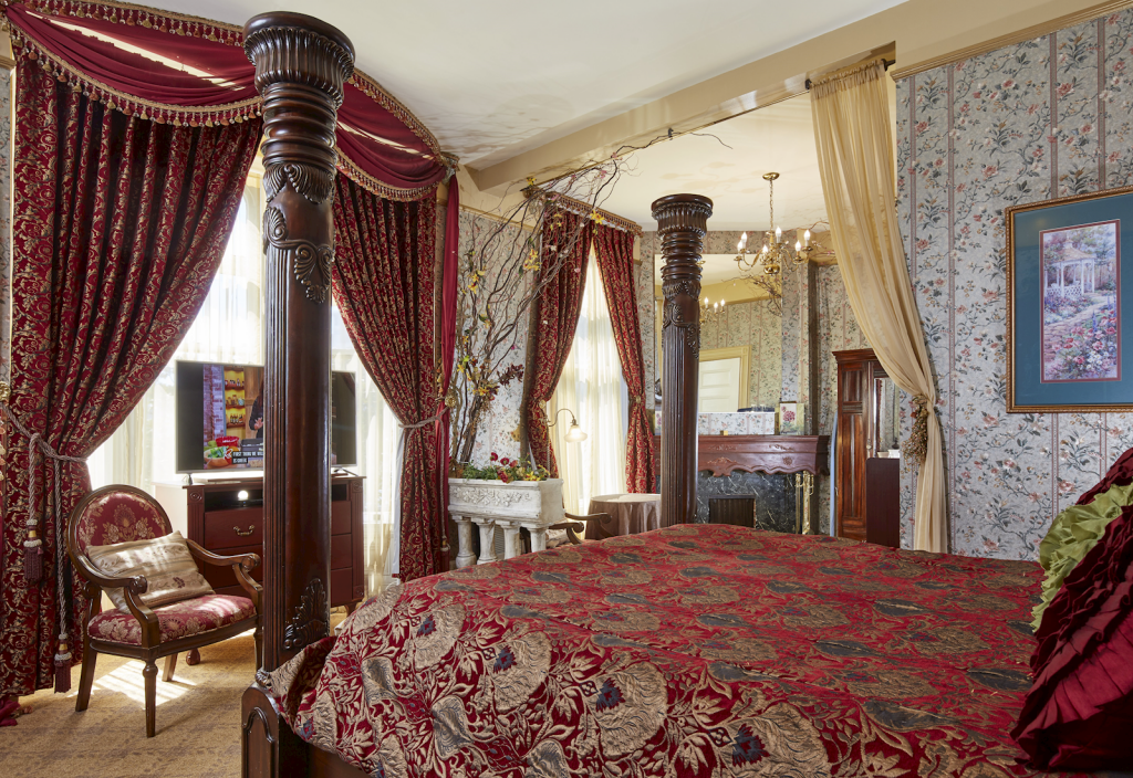 Room with a four-poster bed and floor-to-ceiling window at the Queen Anne Hotel.