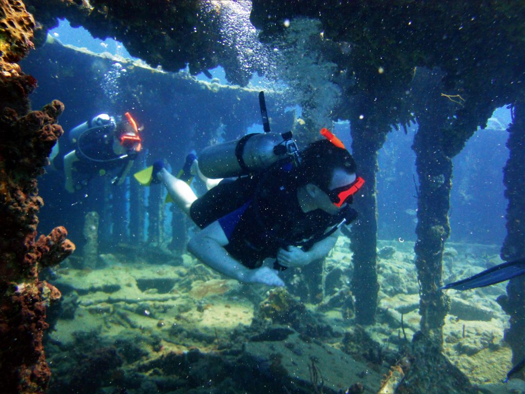 Two men in scuba diving equipment diving near a ship wreckage, one of the fun things to do in St Thomas. 