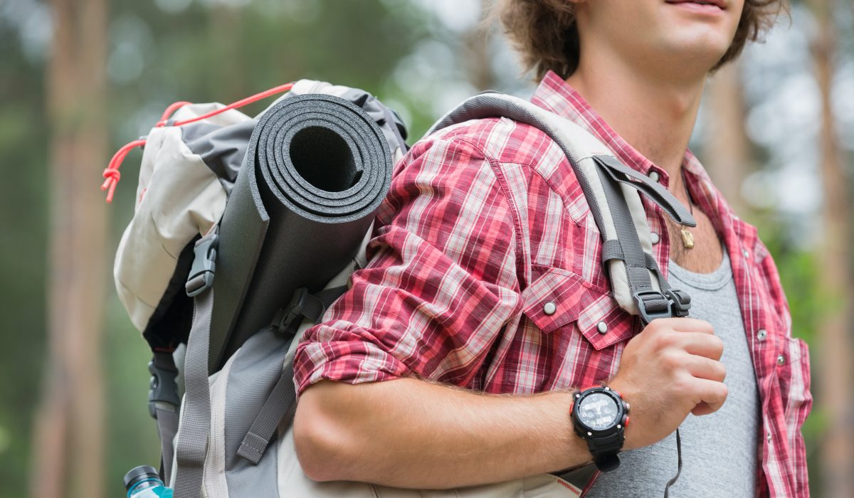 Midsection of male hiker carrying backpack in forest Mid-section of a man wearing one of the best ABC watches, while carrying a camping bag in the woods.
